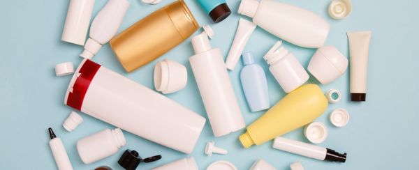 An assortment of blank cosmetic bottles spread out on a pale blue background.