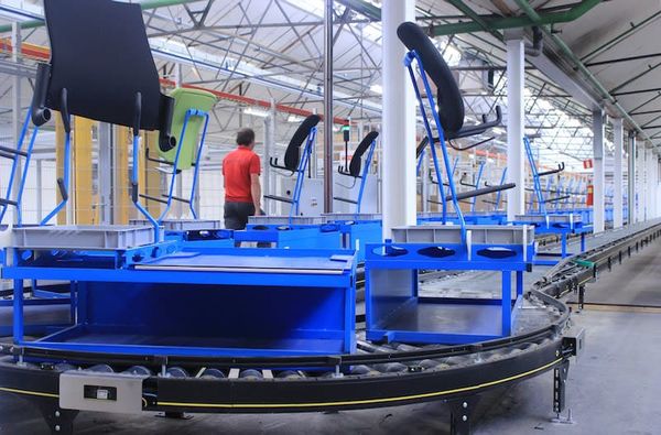 A machine transports modular seat parts inside of a factory