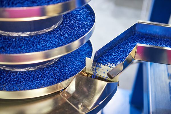 A hopper moves pellets of blue recycled plastic into a concentrically circular moving platform