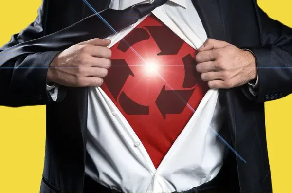 A man wearing a suit is framed to see only his chest, opens the front of his white collared button up shirt to reveal a red undershirt with a recycling symbol, symbolic of a "superhero" 