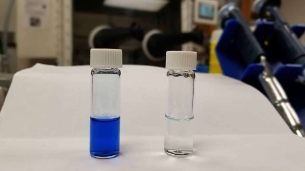 two viles of liquid stand beside eachother, one colored and one clear, implied that the clear one is a successful result of the solvent process