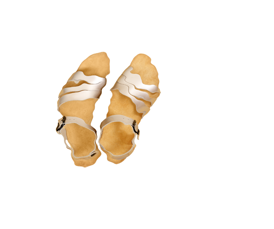 A pair of gold sandals on a white background with effects that make them look distorted.