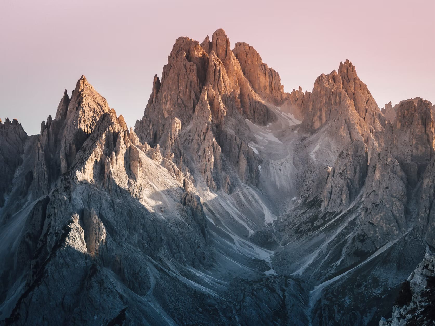 The jagged peaks of the Dolomites UNESCO system glowing pink at sunset, a phenomenon known as Enrosadira in the Italian Alps.
