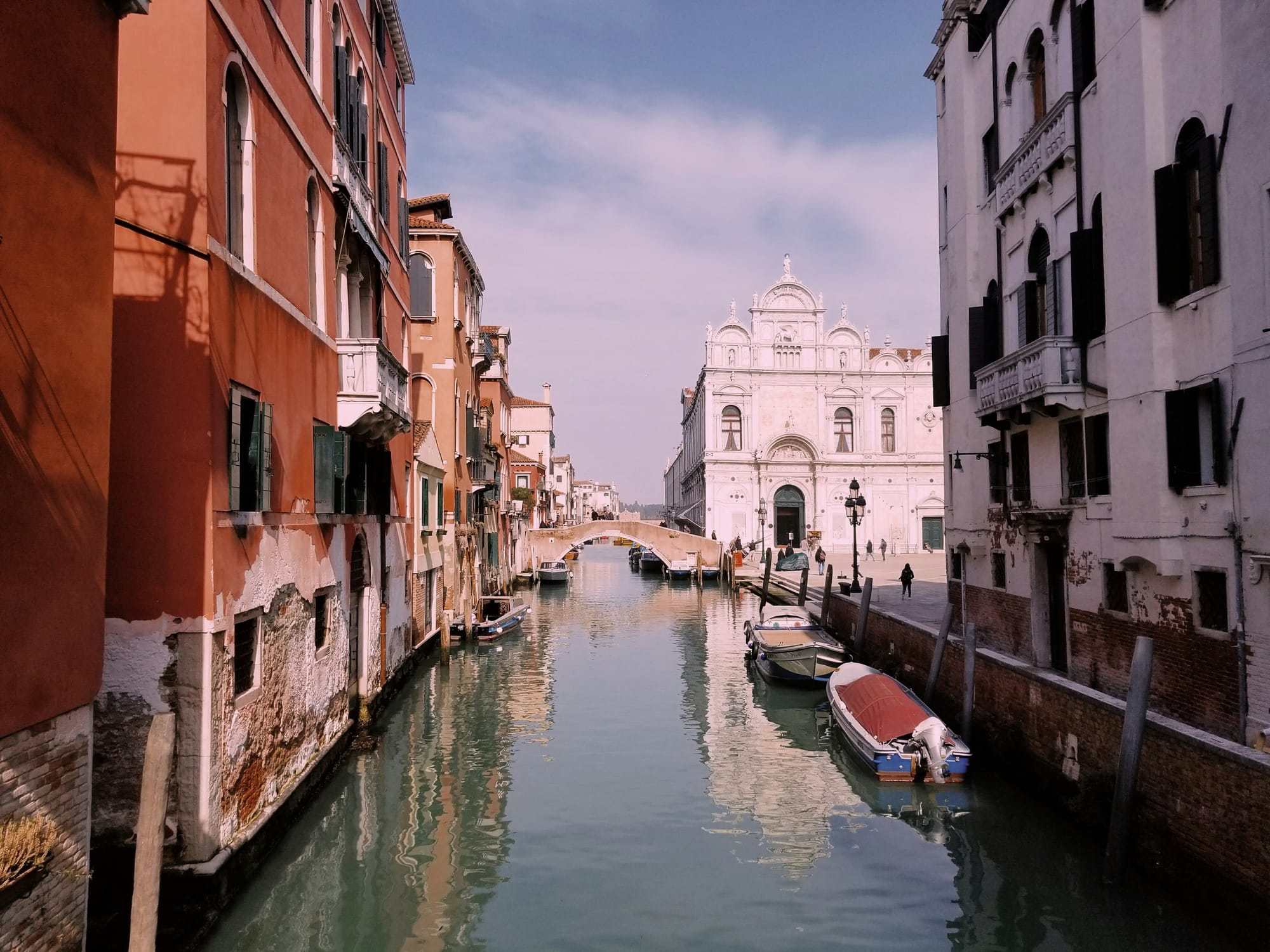 View of one of Venice's canals, complete with its traditional boats, gondolas, and historic buildings.