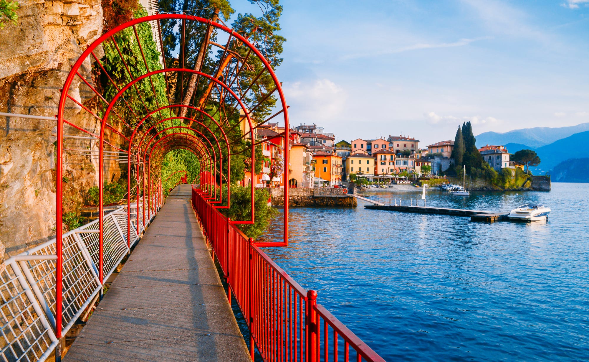 The famous Lovers' Walk (Passeggiata degli Innamorati) in Varenna, featuring its distinct red archway leading towards the colorful village on Lake Como.