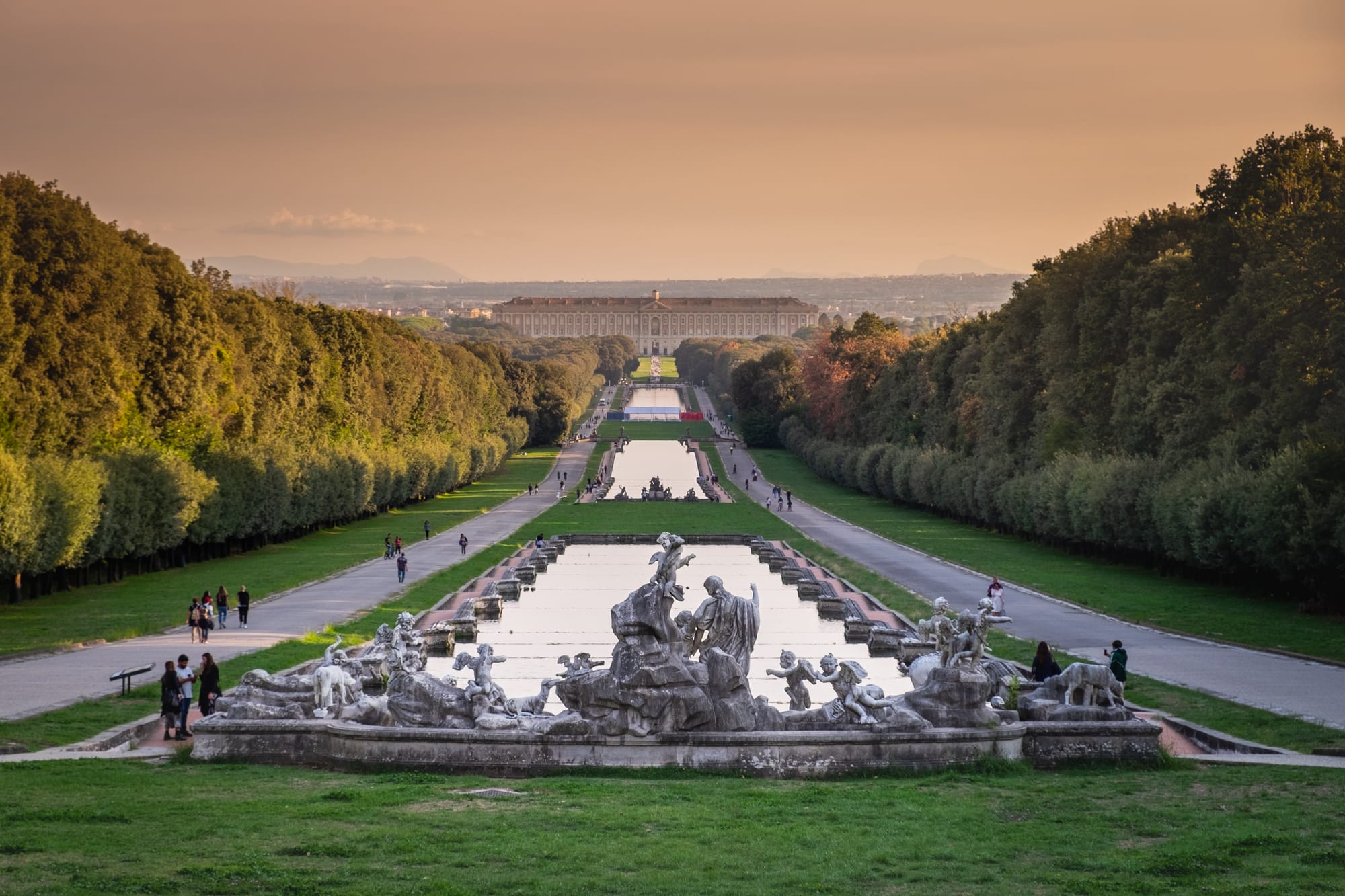 The grand baroque Royal Palace of Caserta viewed from its magnificent gardens, with the long water basin and fountains leading towards the palace.