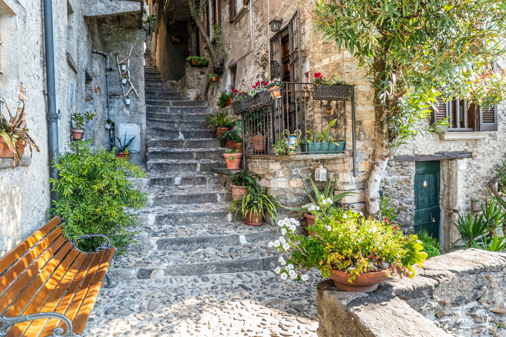 A close-up of the weathered stone steps, known as 'scalotte,' that form a narrow, steep alleyway in the heart of Corenno Plinio, the 'borgo dei mille gradini' on Lake Como.