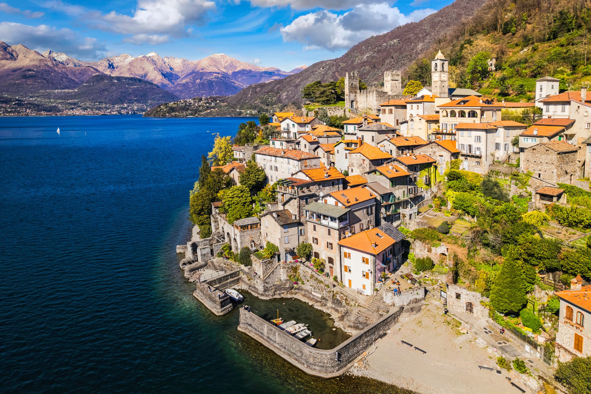 Aerial view looking north over the medieval borgo of Corenno Plinio, showing the Andreani castle and the village's strategic location on the eastern shore of Lake Como, near Dervio.