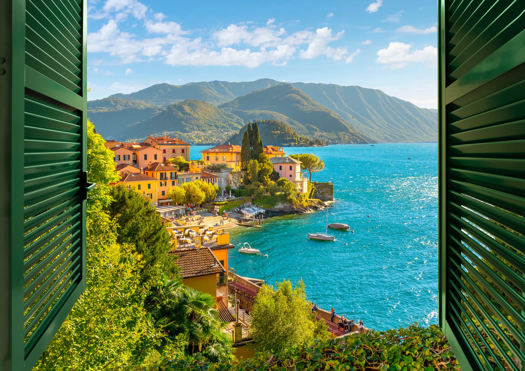 View from an open window with shutters overlooking the picturesque and colorful village of Varenna, with its historic houses on Lake Como.