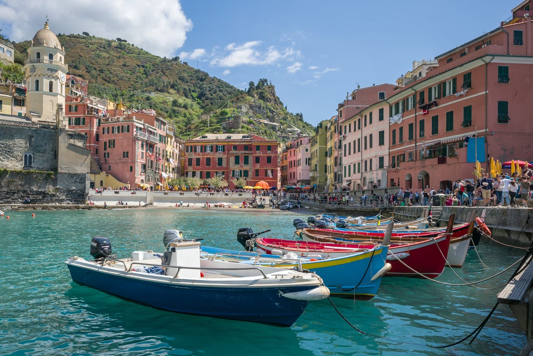 The bustling harbor of Vernazza with its colorful boats and the Church of Santa Margherita d'Antiochia, Italy.
