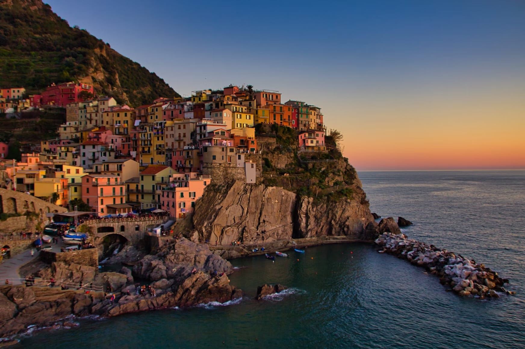 Classic sunset view of Manarola's colorful houses clinging to the cliffs, an iconic scene in Cinque Terre, Italy.