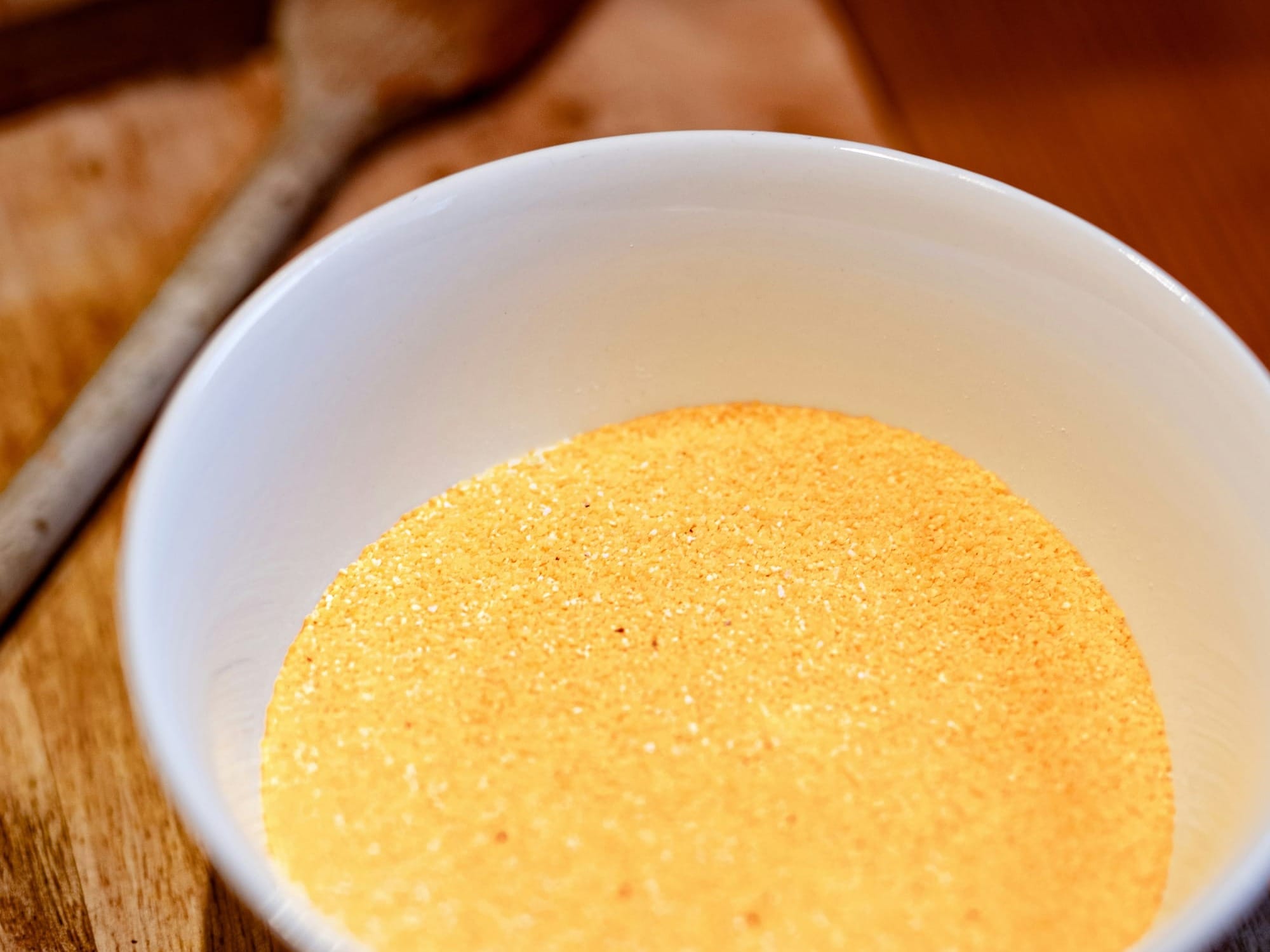 A traditional copper paiolo (cauldron) filled with yellow cornmeal, ready for making polenta, a staple dish of the Italian Alps.