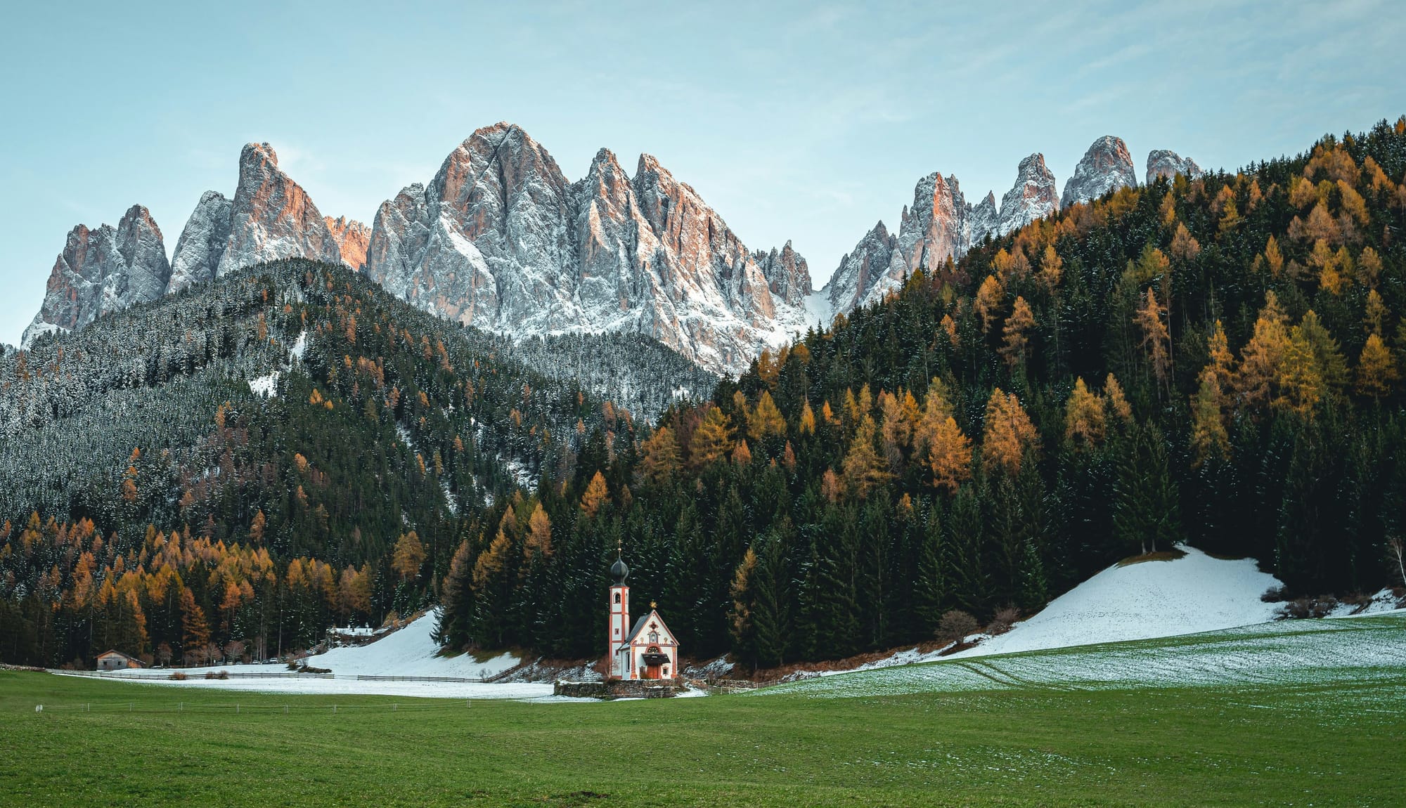 The church of St. Johann in Ranui, a hidden gem in Val di Funes, with the Odle peaks of the Dolomites in the background.