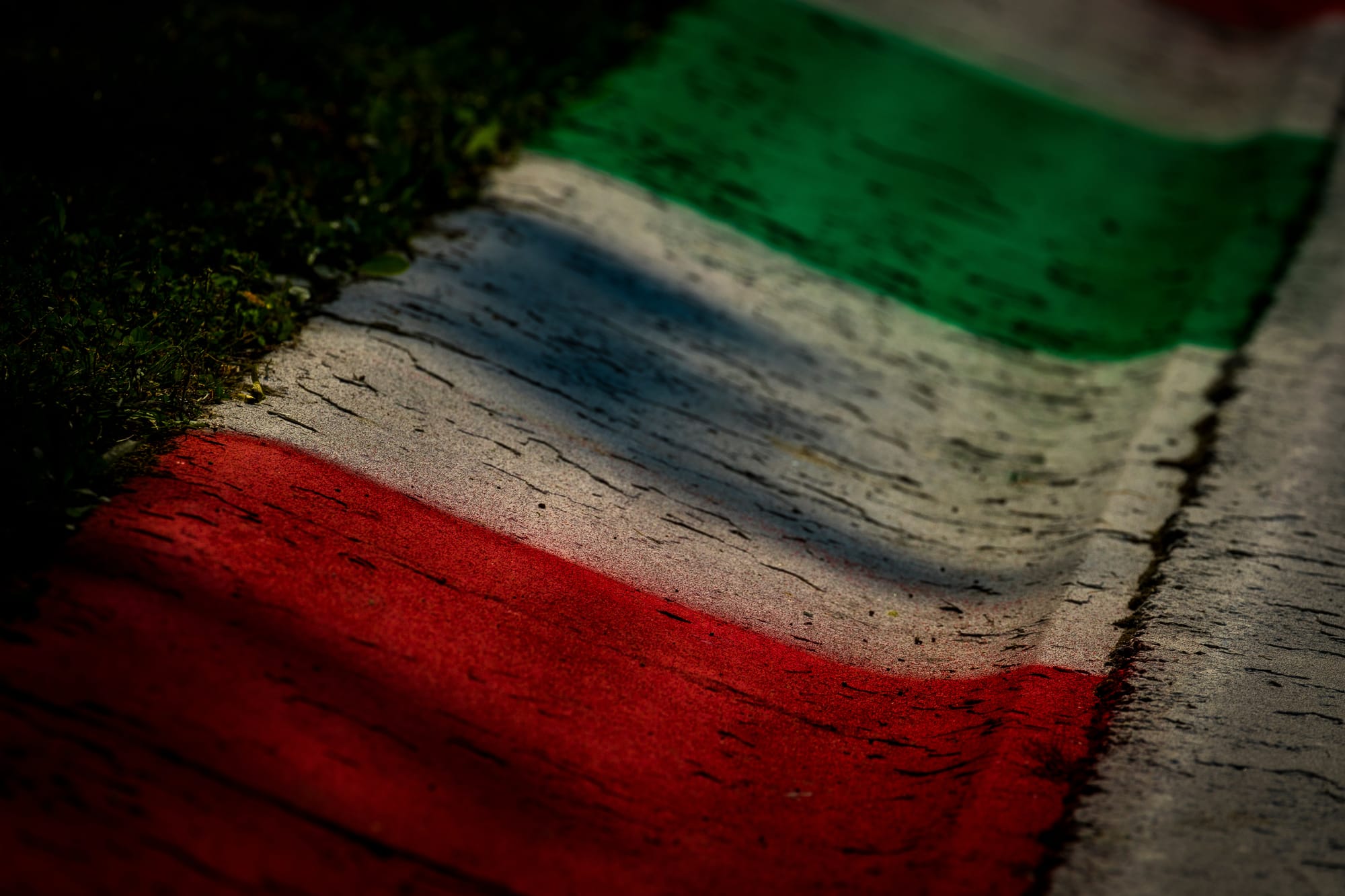 A close-up of a racetrack curb at the Monza circuit painted with the green, white, and red colors of the Italian flag.