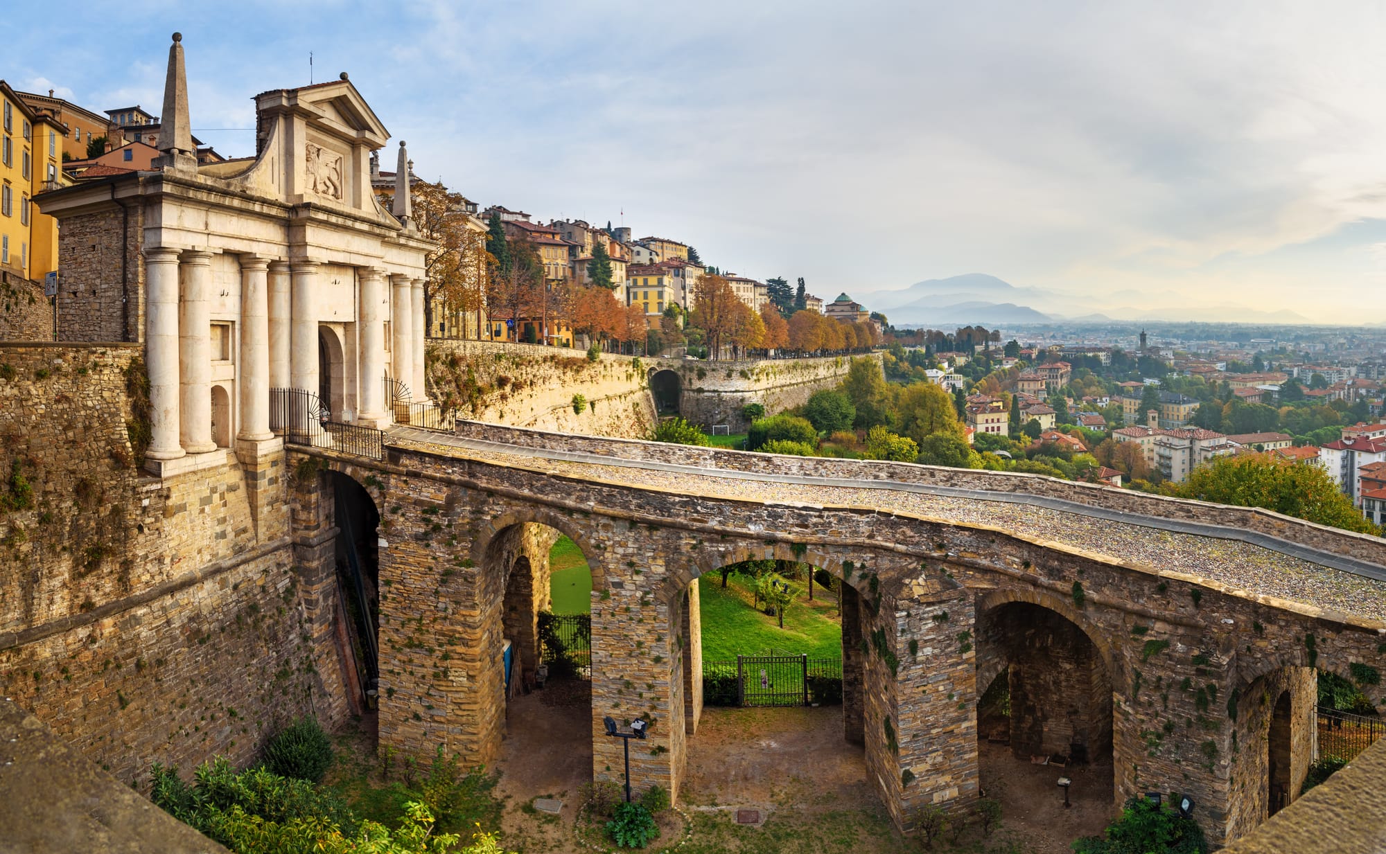 Morning view of the iconic Porta San Giacomo, a white marble gate in the UNESCO Venetian Walls of Bergamo's Città Alta.