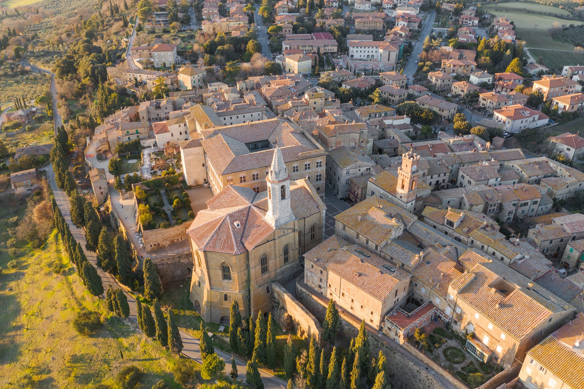 An aerial view of the Renaissance town of Pienza, showing its historic center, the Duomo, and the surrounding Tuscan countryside of the Val d'Orcia.
