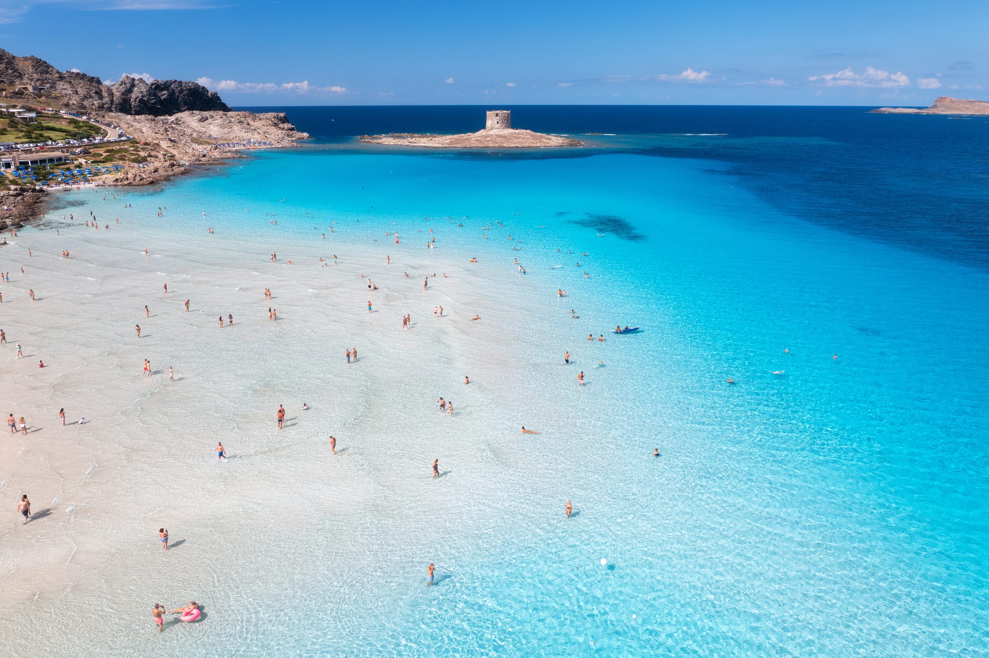 Aerial view of the famous La Pelosa beach in Stintino, Sardinia, showing its iconic white sand, shallow turquoise water, and the ancient watchtower. One of the best beaches in Italy.