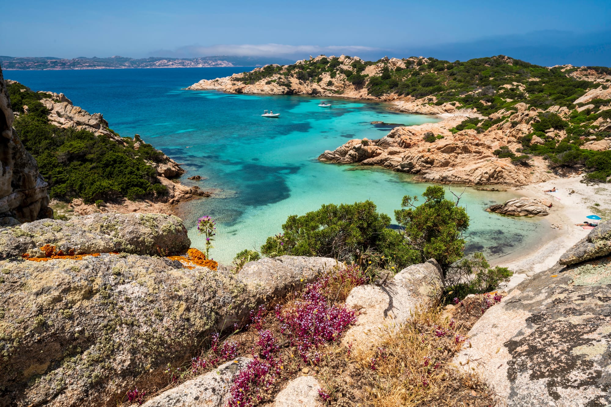 Panoramic view of the pristine beach and vibrant turquoise waters of Cala Napoletana, La Maddalena National Park, Sardinia.