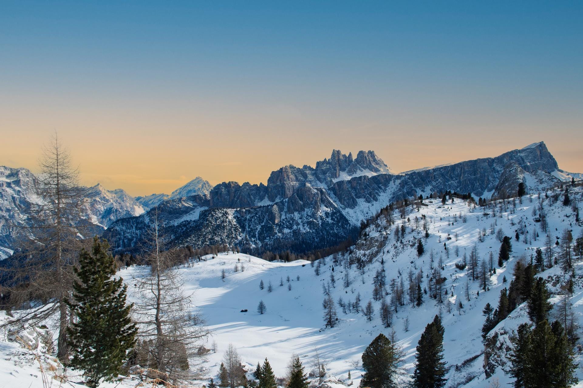 A panoramic winter view of the Cinque Torri rock formations in the Ampezzo Dolomites near Cortina d’Ampezzo, showing the vast snowy landscape.