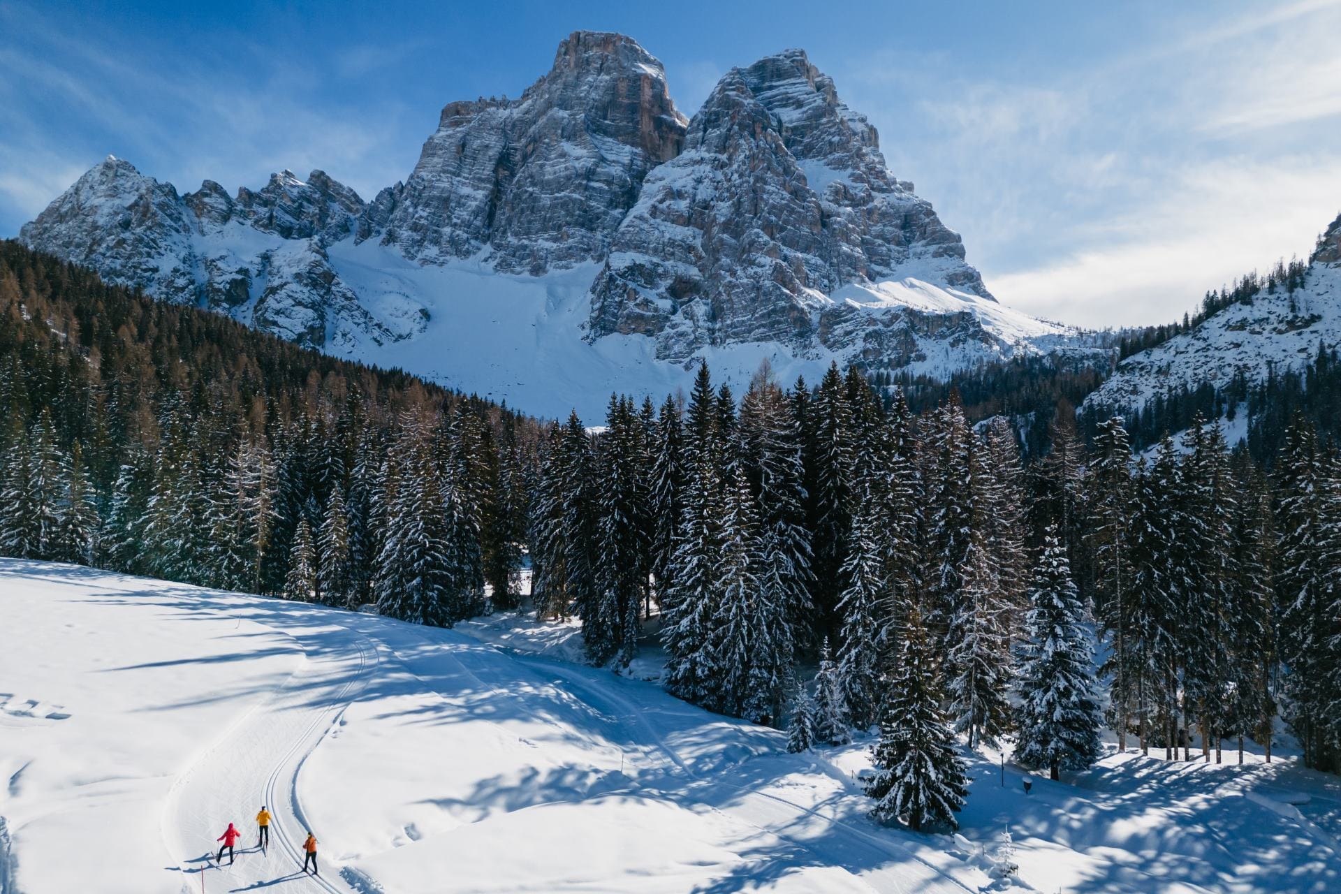 Aerial view of a perfectly groomed cross-country ski track winding through the snow at the base of the monumental mount Pelmo in Val Fiorentina.