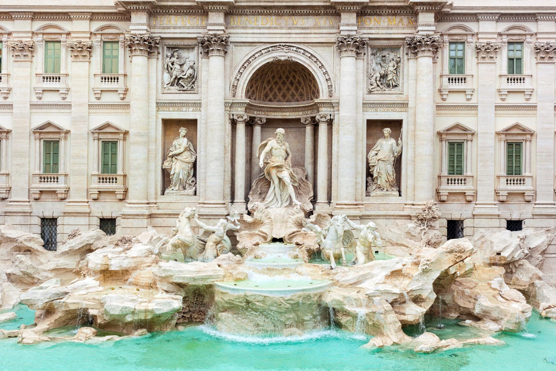 Baroque architecture of the Trevi Fountain in Rome with blue water and Neptune statue.