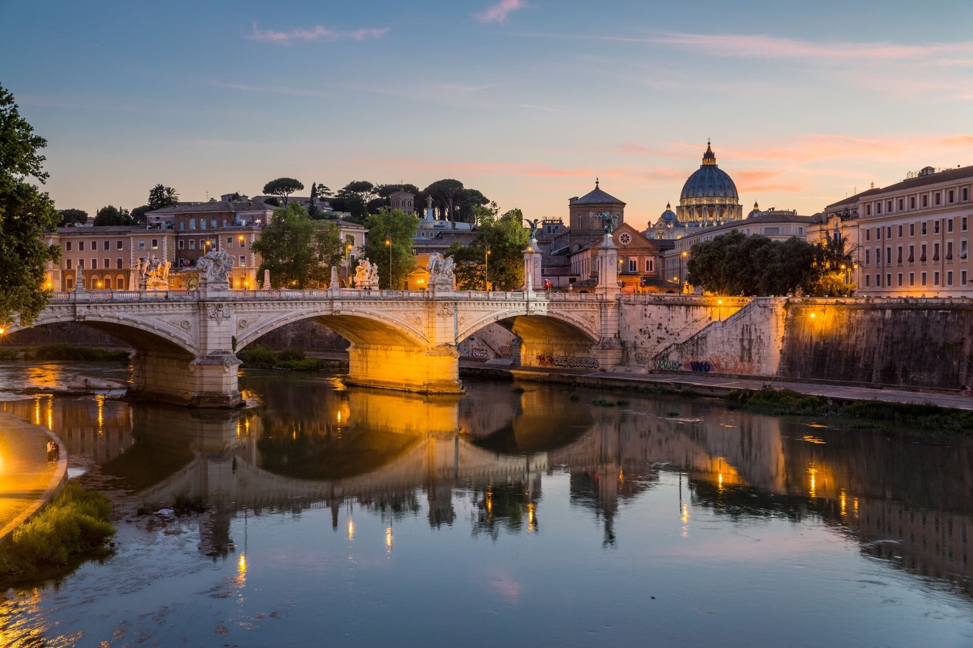 View of St. Peter's Dome and the Tiber River from the Bridge of Angels (Ponte Sant'Angelo) at dusk.