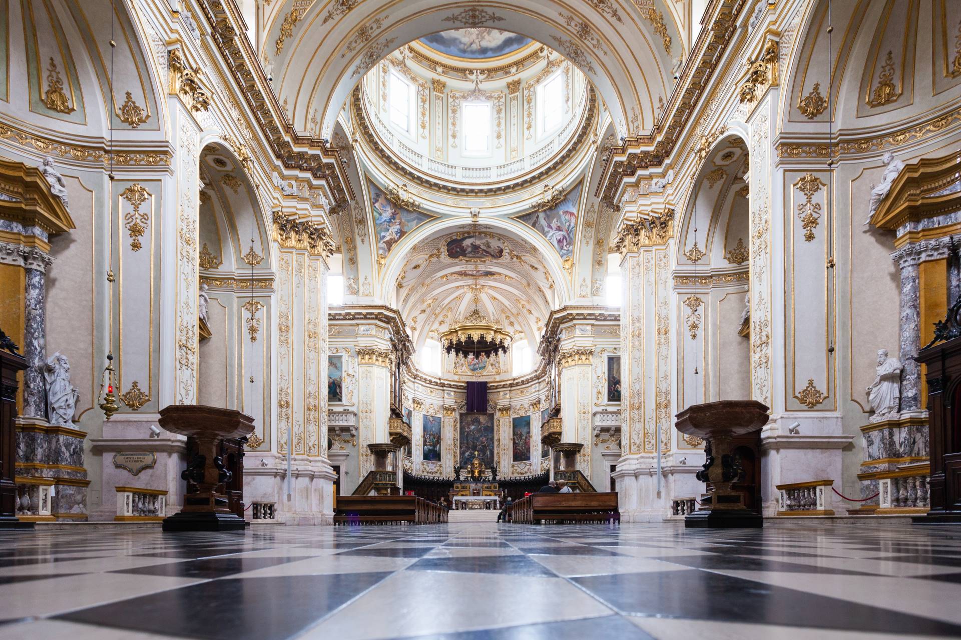 The opulent interior and central nave of the Bergamo Cathedral decorated with frescoes and gold detailing.