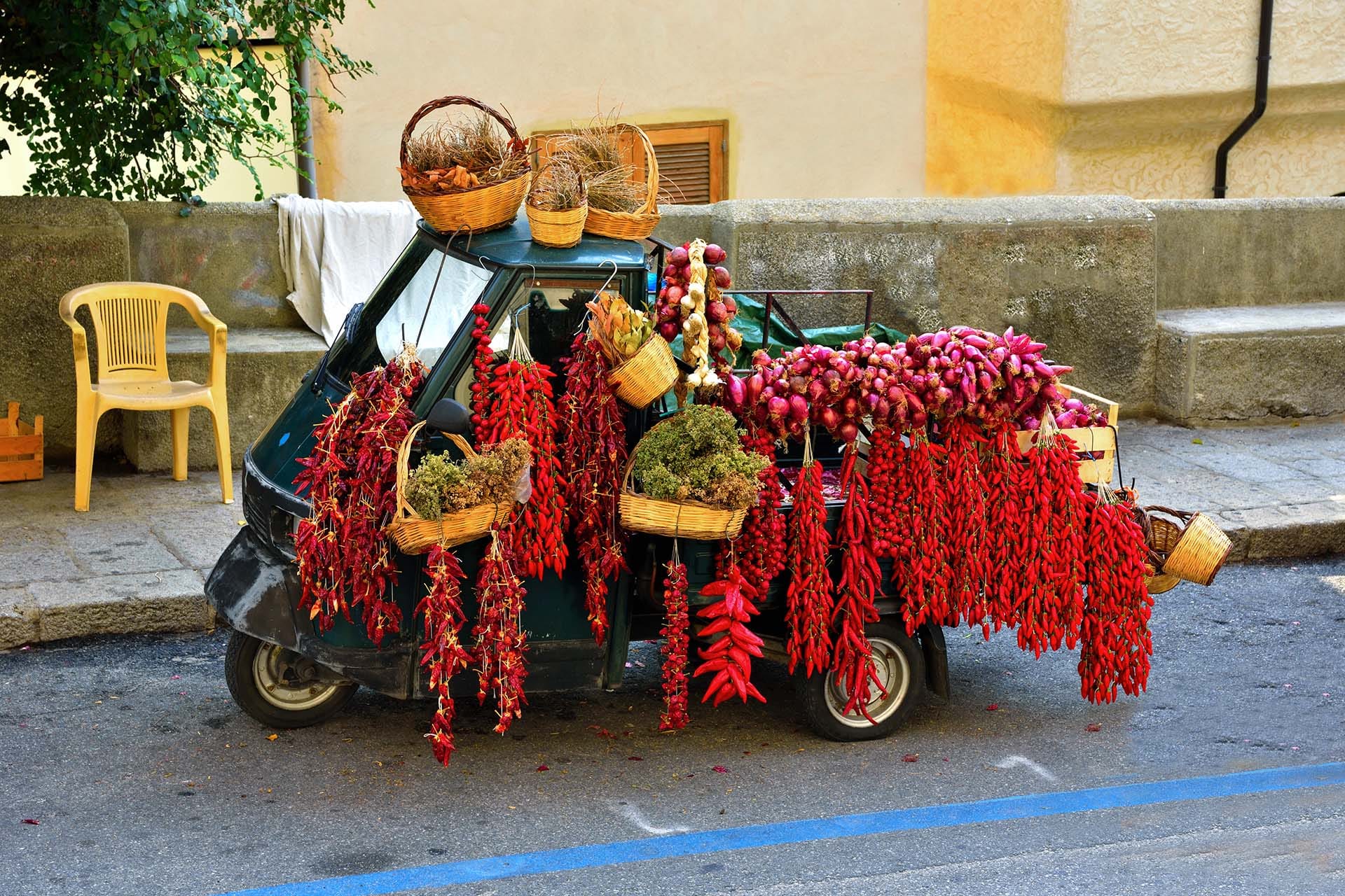 Traditional Italian Ape Car loaded with Calabrian peperoncini and Tropea red onions on a country road