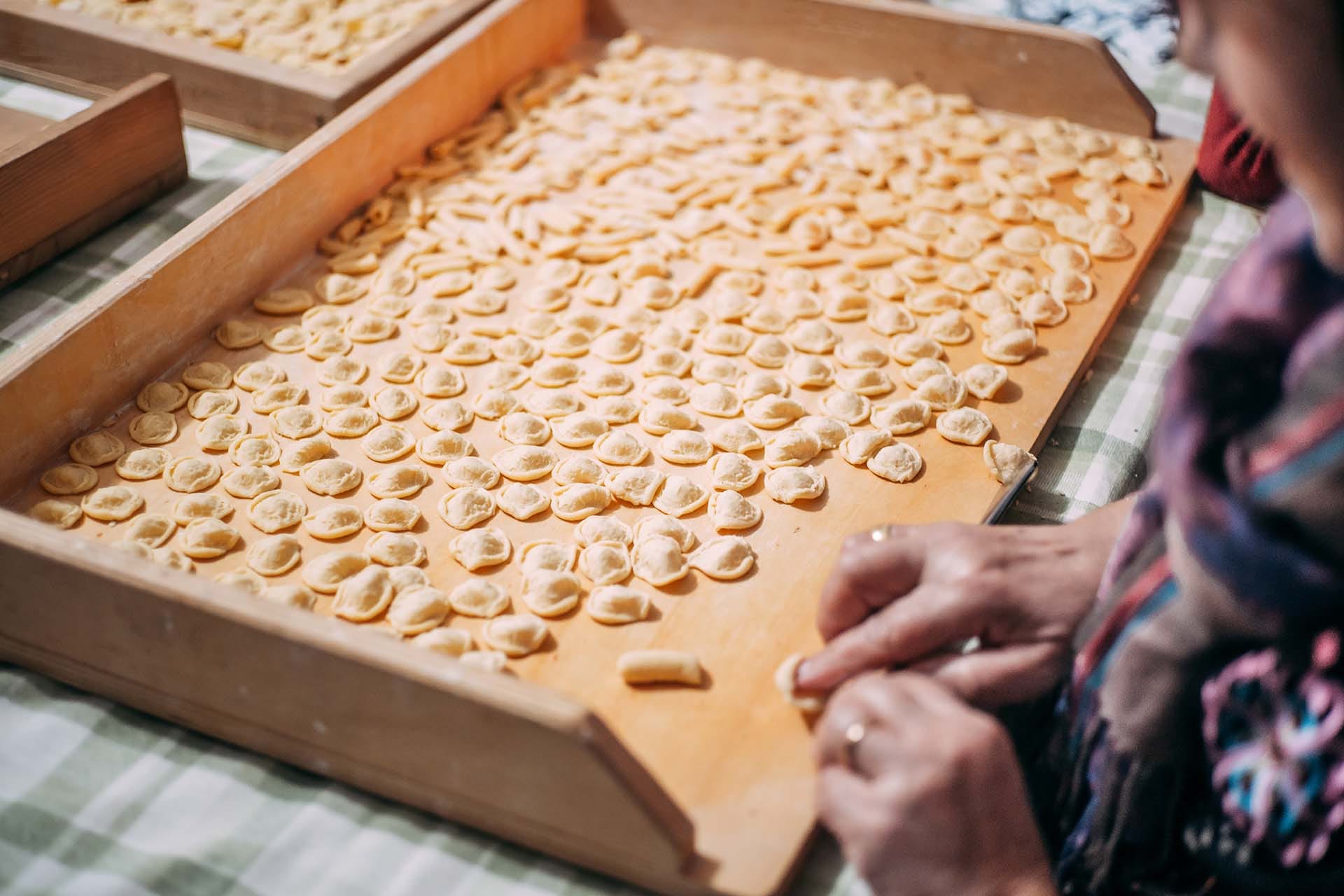 Close-up of elderly Italian woman's hands shaping homemade pasta dough, preserving a centuries-old artisan food tradition of Italian regional cuisine.