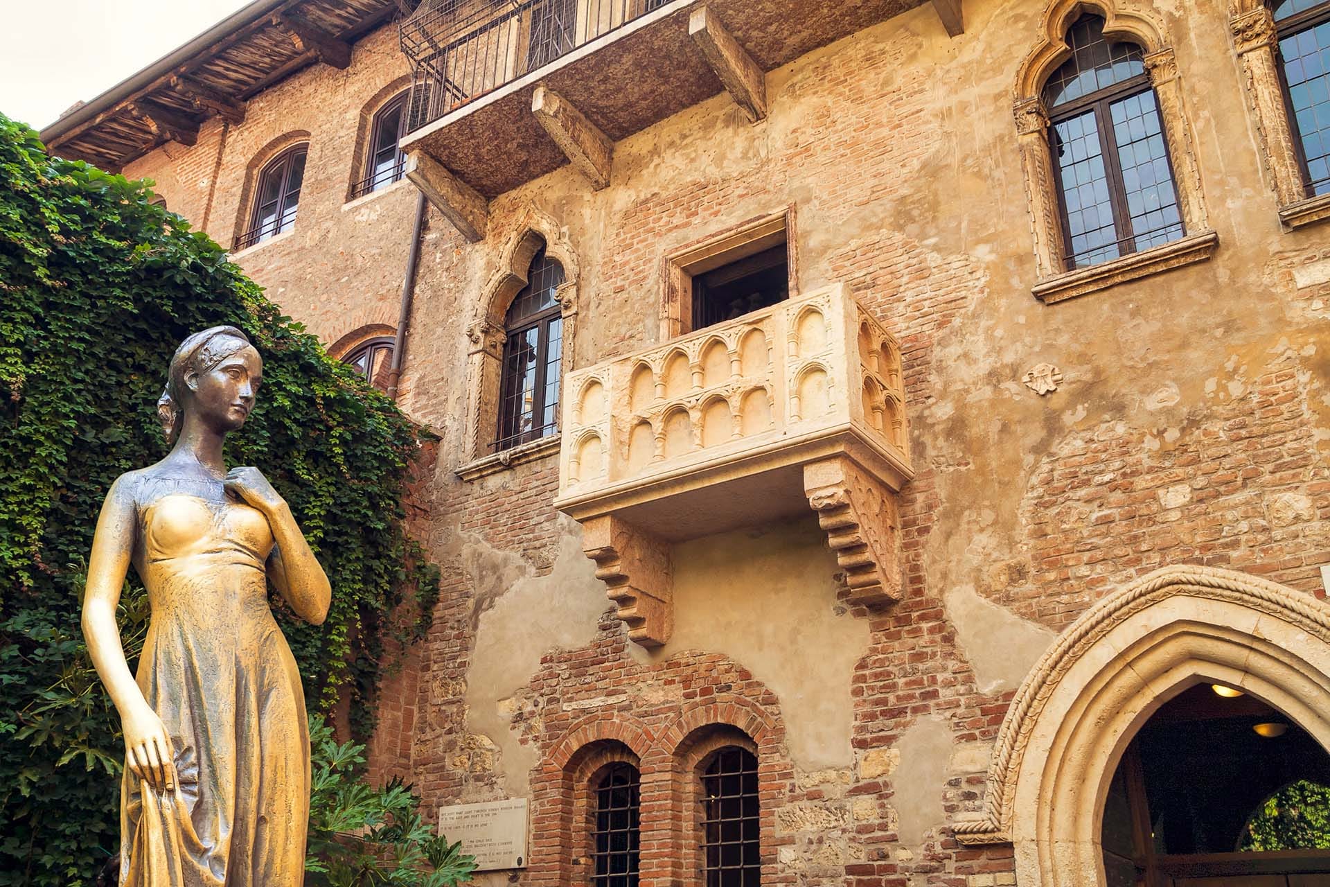 The bronze statue of Juliet with her famous balcony in the courtyard of Casa di Giulietta, Verona, Italy, a celebrated cultural landmark and travel destination.