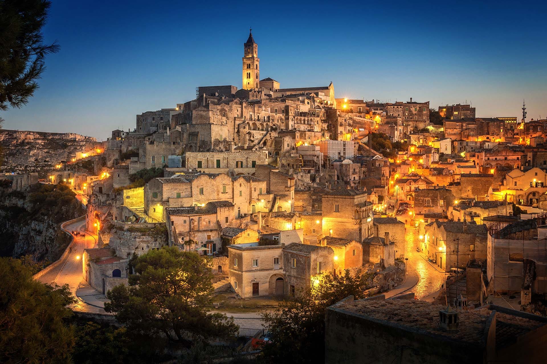 The ancient cave city of Matera (Sassi di Matera) glowing with warm golden light at dusk, UNESCO World Heritage Site, Basilicata, southern Italy.