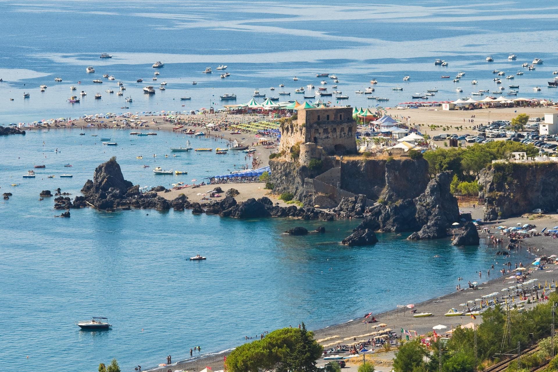 Panoramic view of the historical Torre di Fiuzzi standing on a rocky outcrop in Praia a Mare, surrounded by the crystal-clear waters of the Calabrian coast.