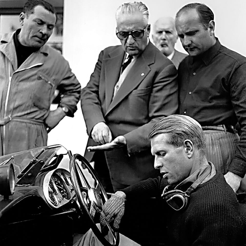Enzo Ferrari pointing at a detail as Peter Collins sits in a Ferrari 335 S before the 1957 Mille Miglia