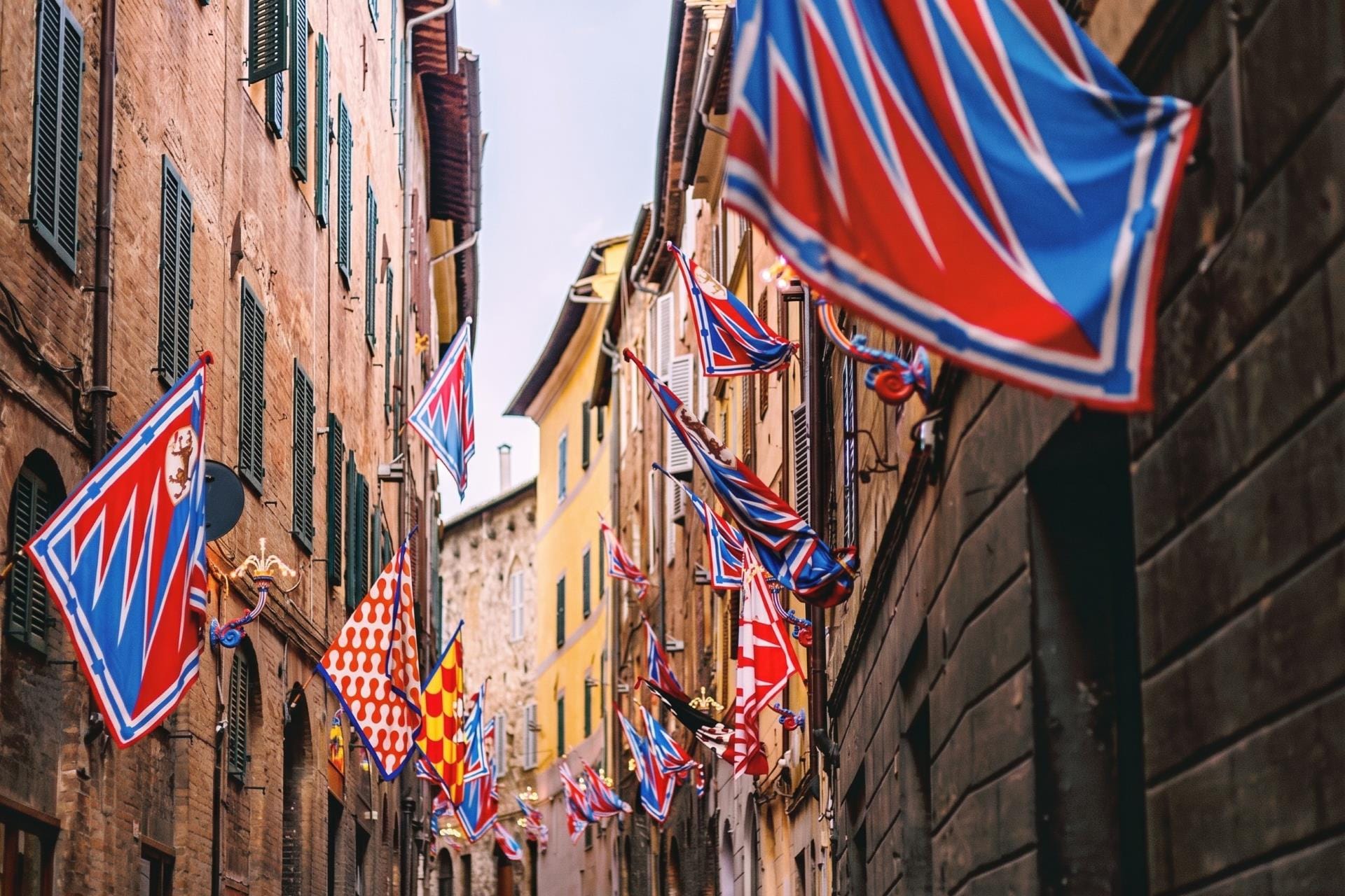 Contrade flags in the colors of rival districts hung over a Siena street before the Palio