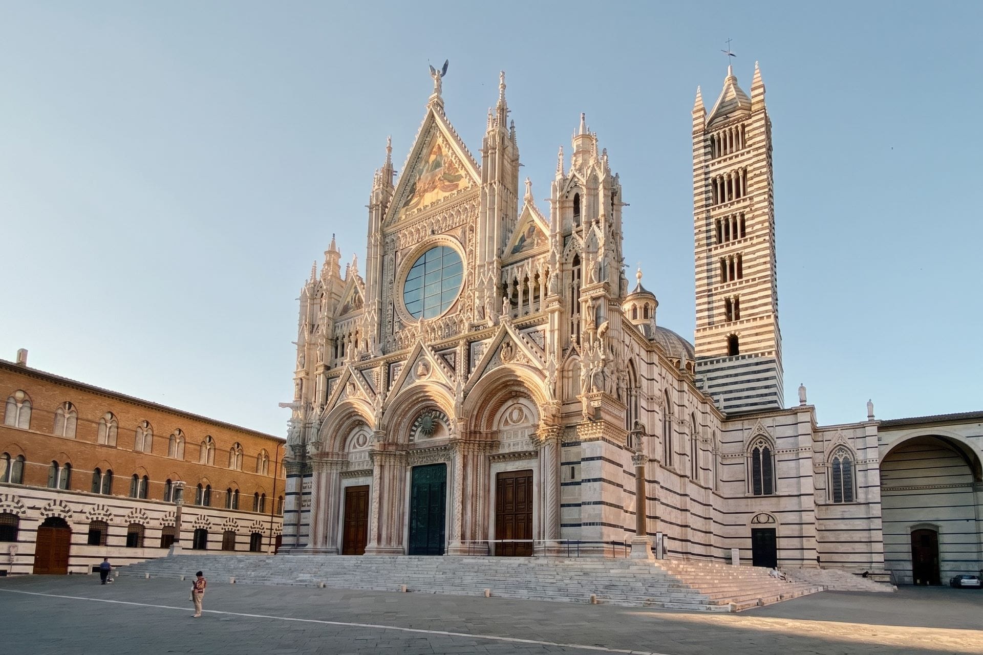 Siena Cathedral marble facade and striped campanile above an empty Piazza del Duomo at early light
