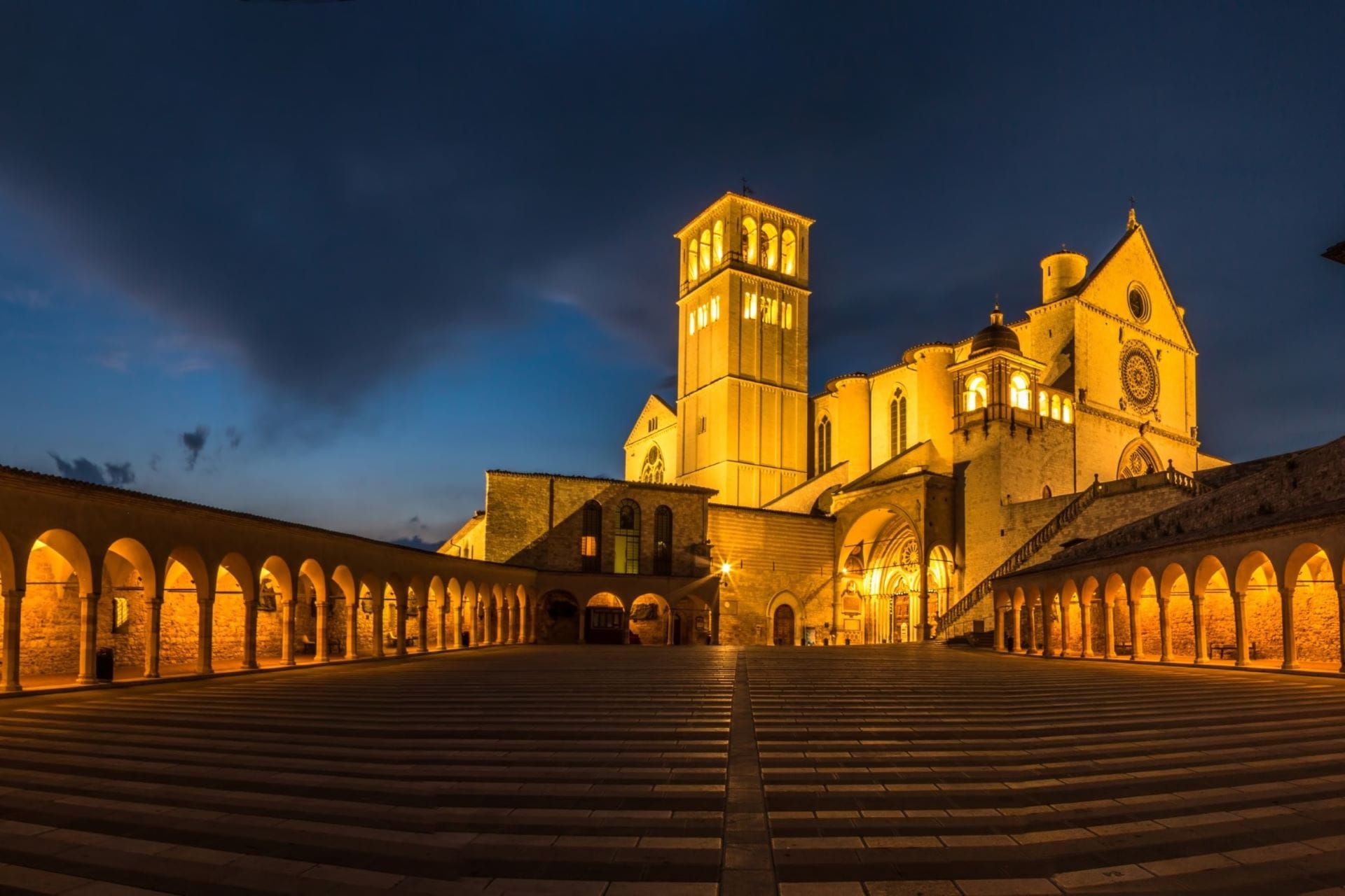 Basilica of San Francesco and its arcaded cloister lit at blue hour in Assisi