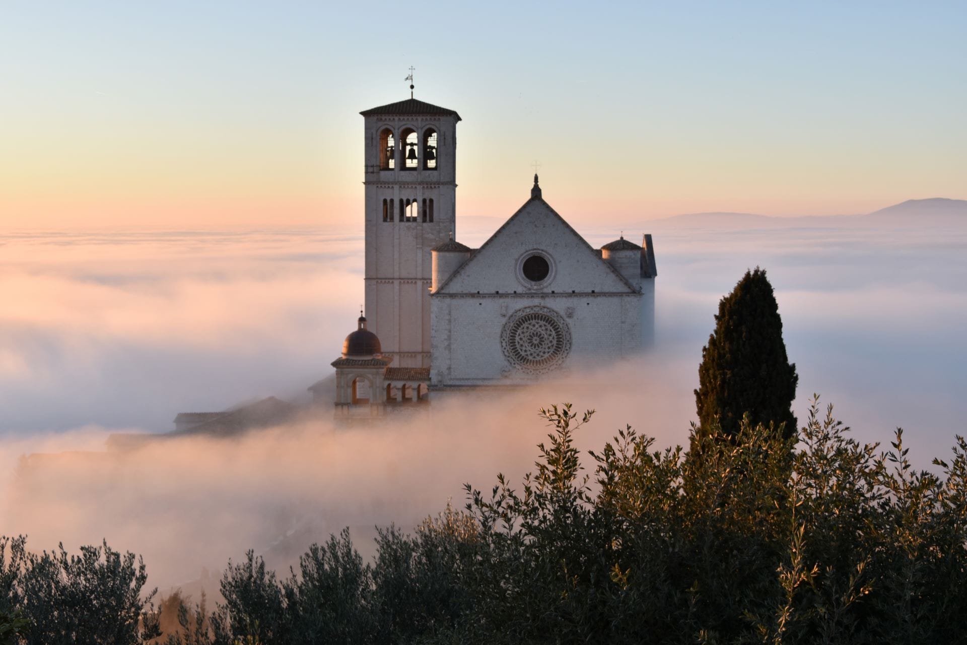 Basilica of San Francesco rising above autumn fog in the Umbrian valley, Assisi