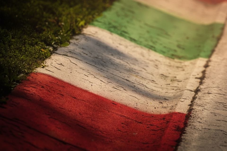 Close-up of a race curb painted in green, white and red at the edge of the track. / Image edited with ai from a reference photograph