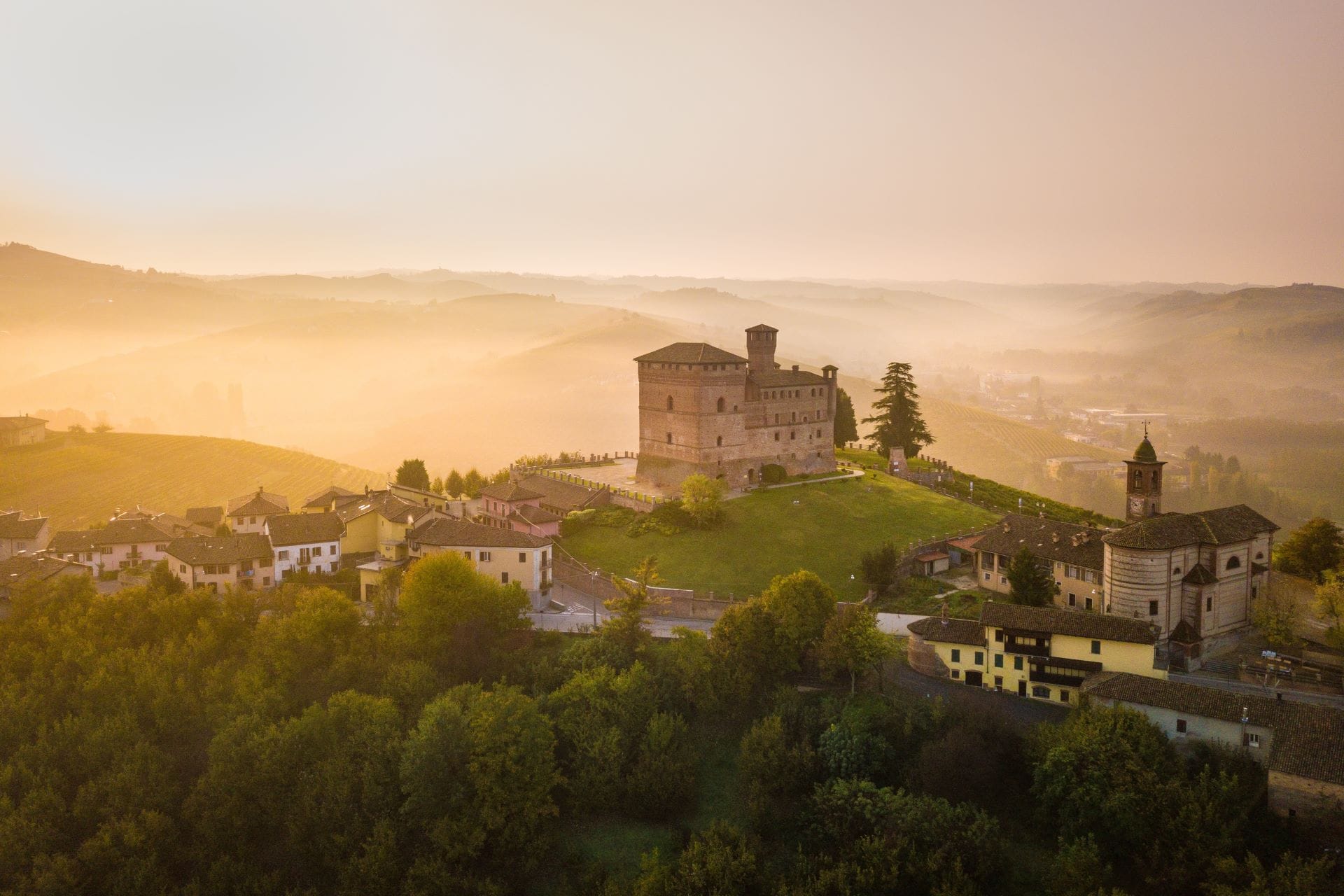 Castello di Grinzane Cavour at sunrise above the fog-covered vineyards of the Langhe