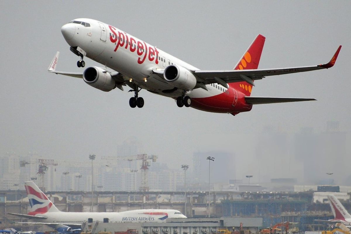 An Indian-operated SpiceJet Boeing 737-800 aircraft (foreground) takes off as a British Airways Boeing 747-400 aircraft (background) sits on the tarmac at the international airport in Mumbai 