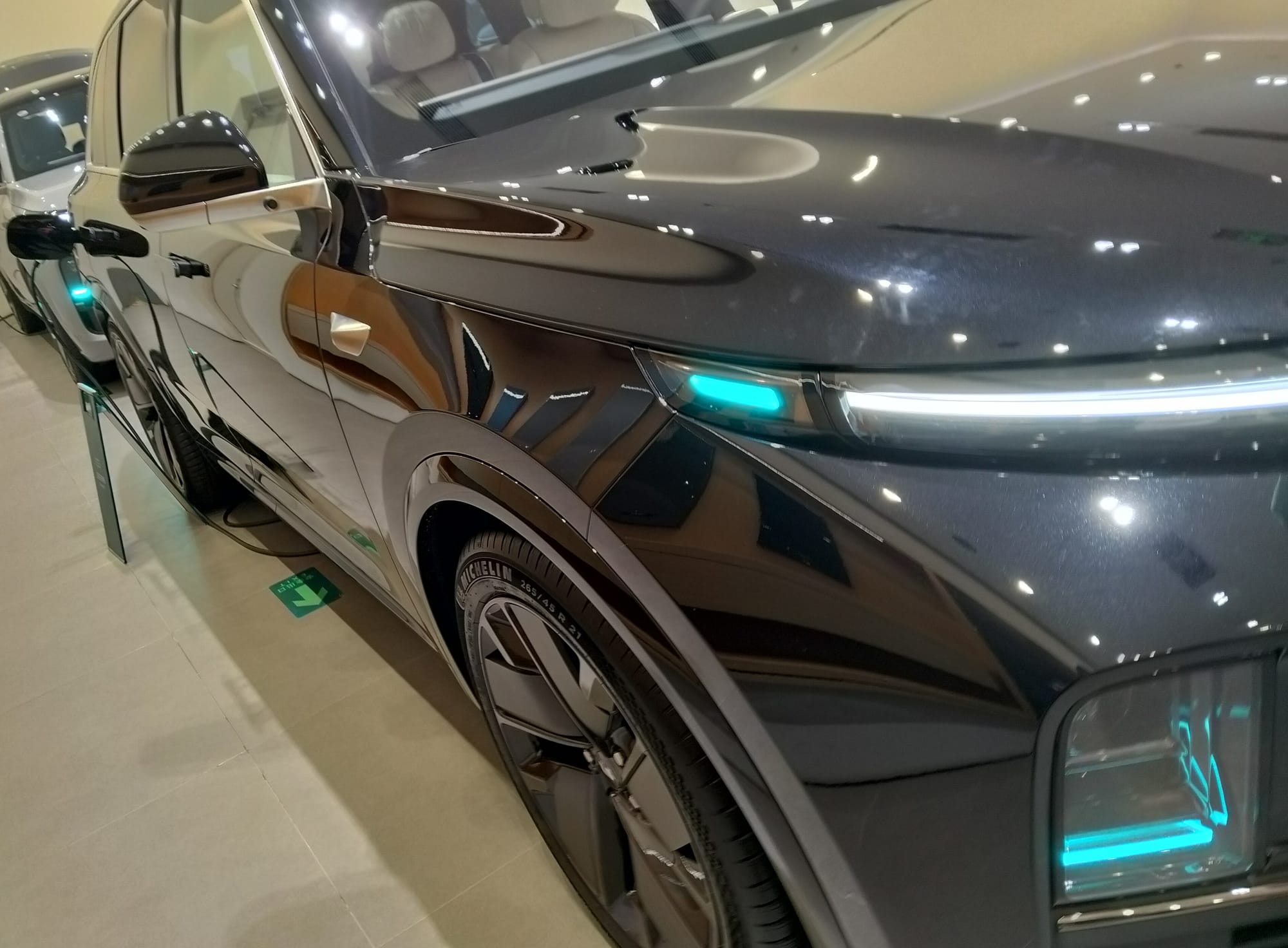 Front right corner of a car with turquoise lights adjacent to the headlights.