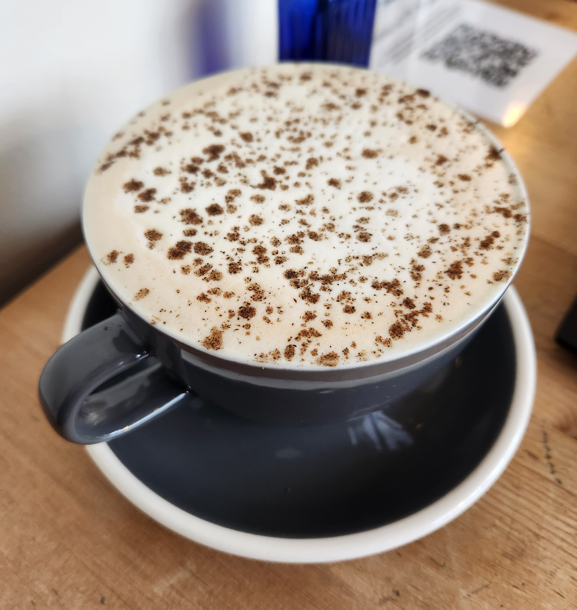 A tea latte drink in a big grey mug, with a frothy top and dusted with vanilla.