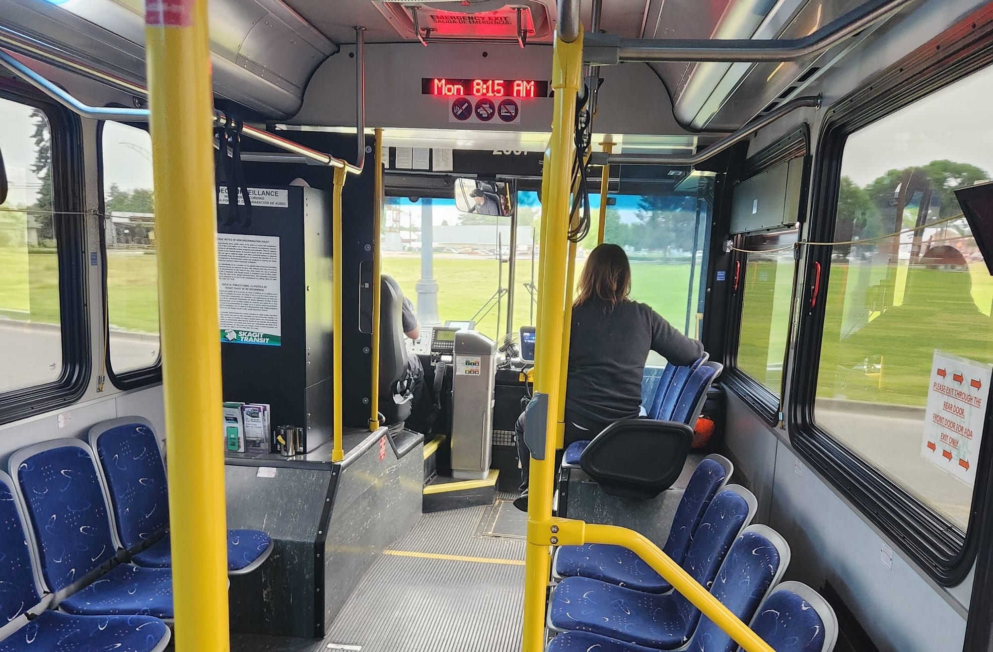 An interior shot of a bus with blue seats and yellow poles and railings.