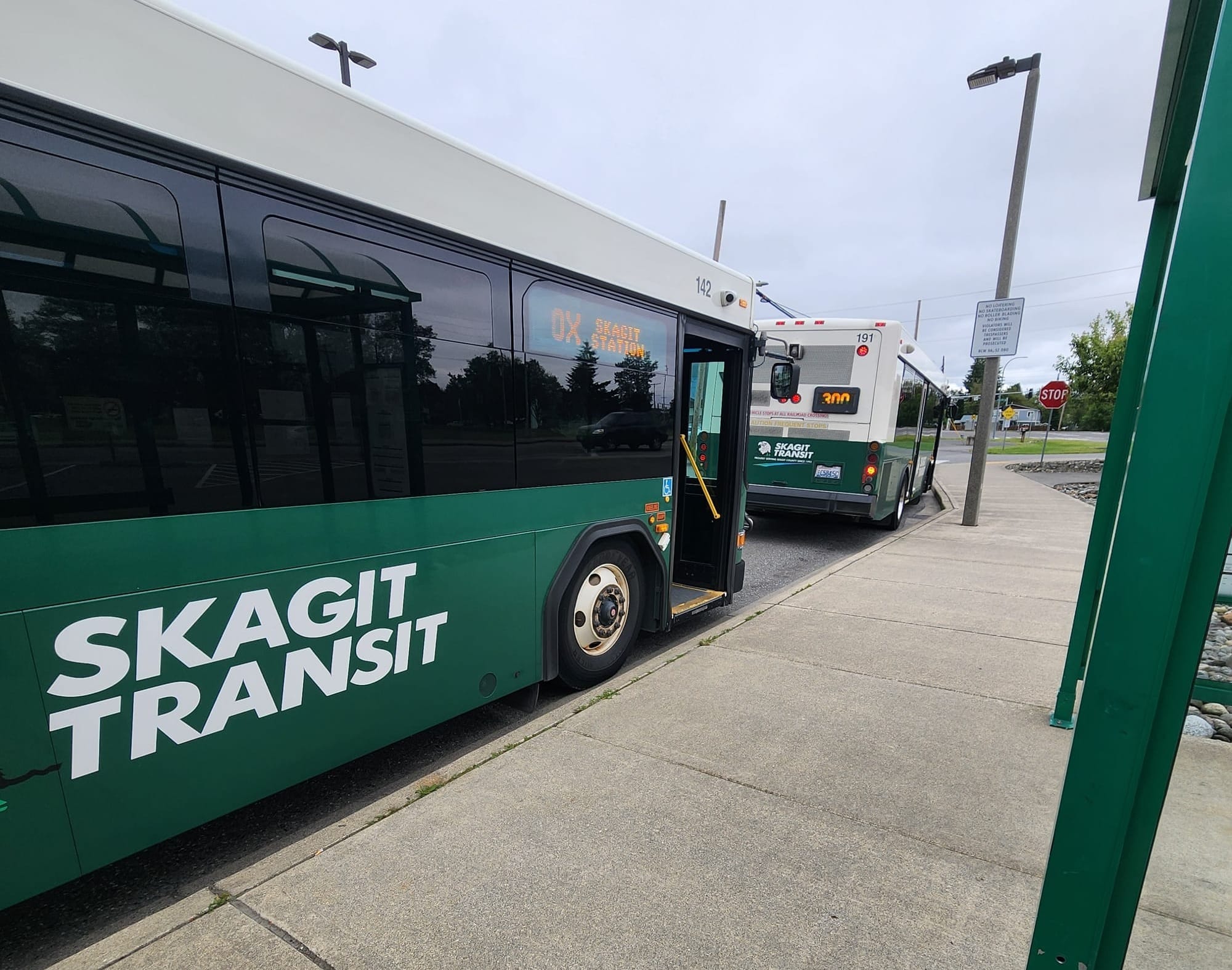 Two Skagit Transit buses are laying over at a park and ride facility.