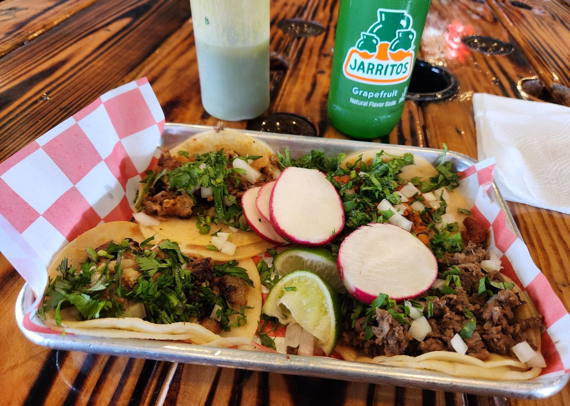 A plate of four tacos with plenty of cilantro, onions.