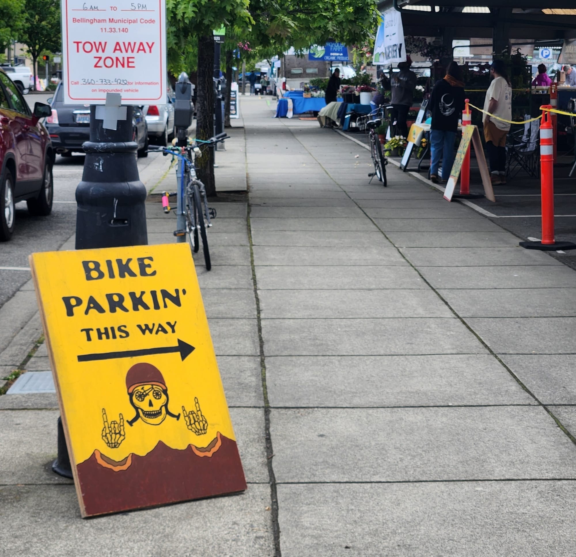 A sidewalk sandwich board reading "Bike Parkin' This Way"