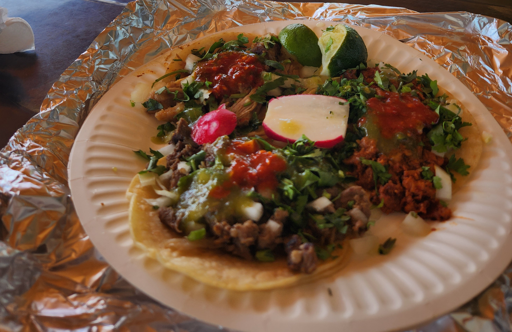 A paper plate with three tacos.