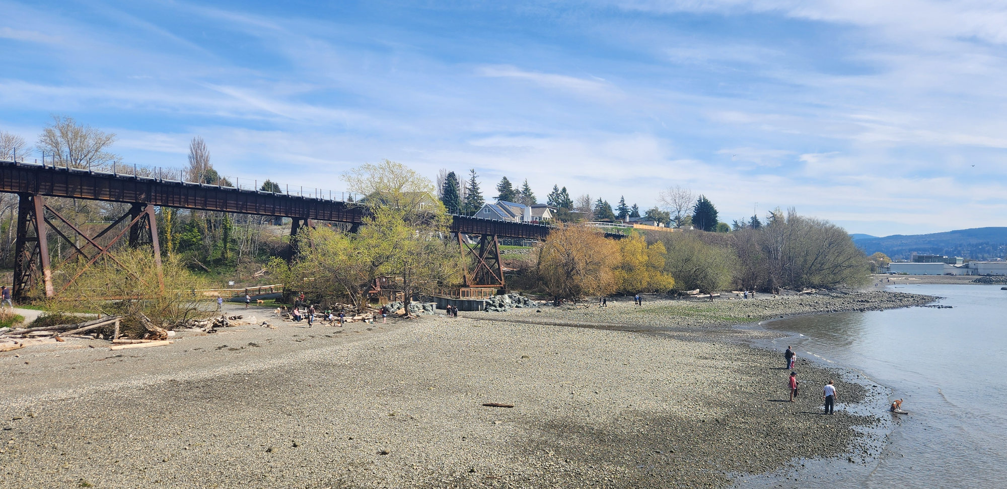 A rocky beach with a few people exploring the waterline.