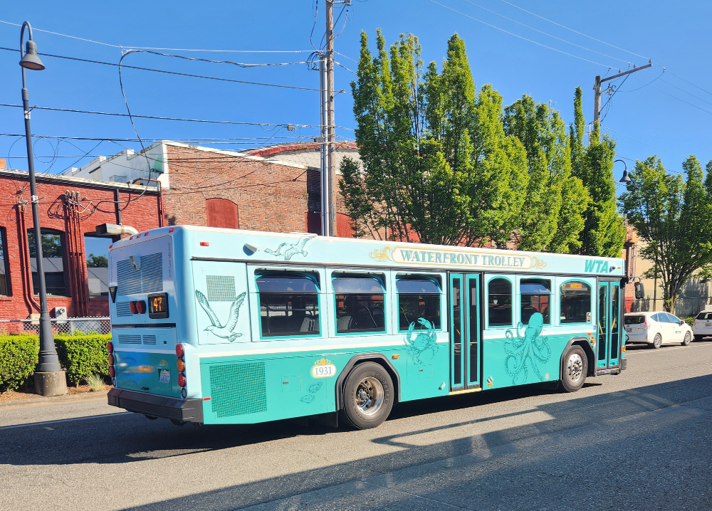 A light blue bus reading Waterfront Trolley with a fun wrap including an octopus and crab