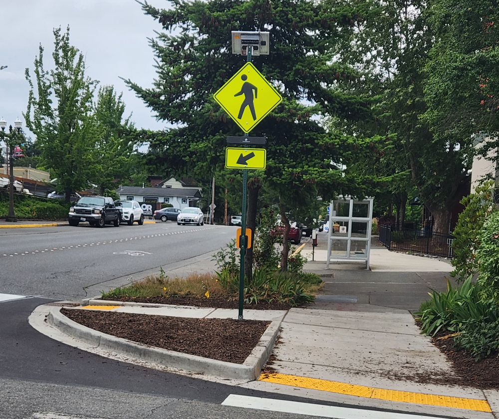 Although the newly installed Rectangular Rapidly Flashing Beacon (RRFB) for the crosswalk at 12th Street & McKenzie Avenue in Fairhaven is clearly visible to southbound motorists, it's blocked by a tree for northbound motorists.